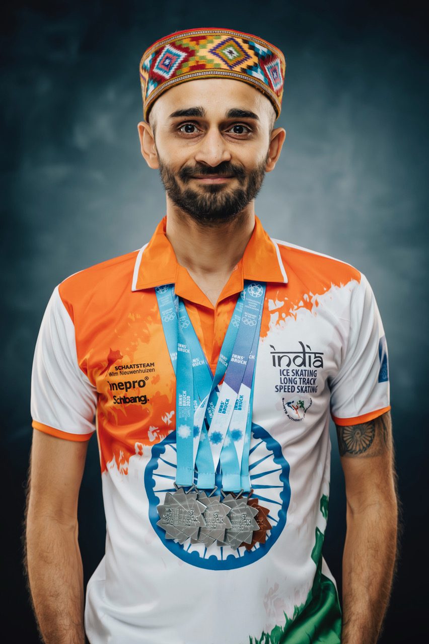 Studio portrait of Vishwaraj in India kit and a traditional Himalayan cap, medals around his neck